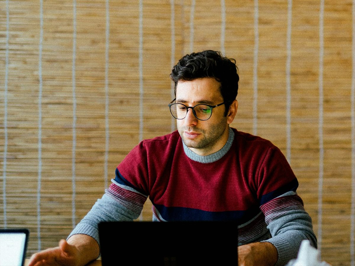 اپراتور پشت میز کار، متمرکز روی لپتاپ باز